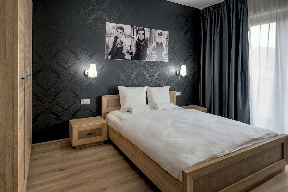 A modern bedroom with a wooden bed, two bedside tables, and a wall-mounted light fixture.