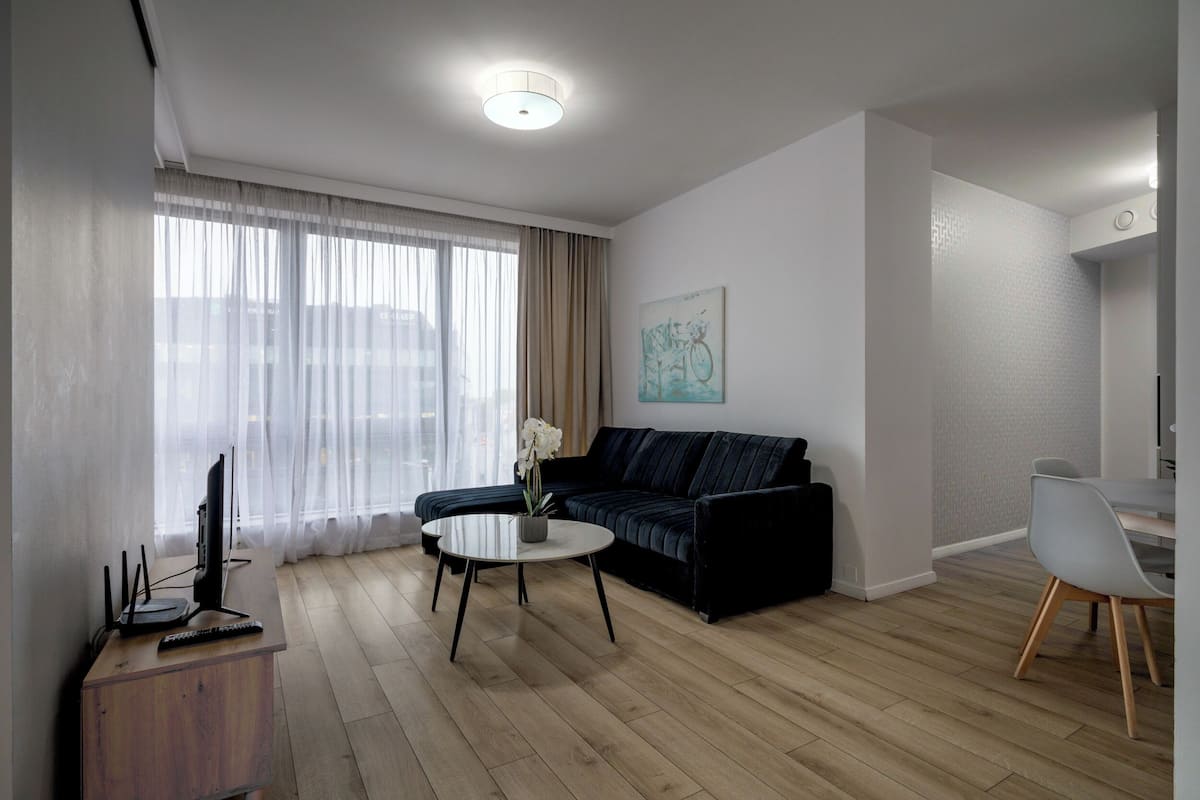 A modern living room with a sofa, a coffee table, and a TV on a wooden cabinet.