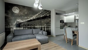 Ein modernes Wohnzimmer mit einem grauen Sofa, einem Holztisch und einem Stadtbild-Wandgemälde.