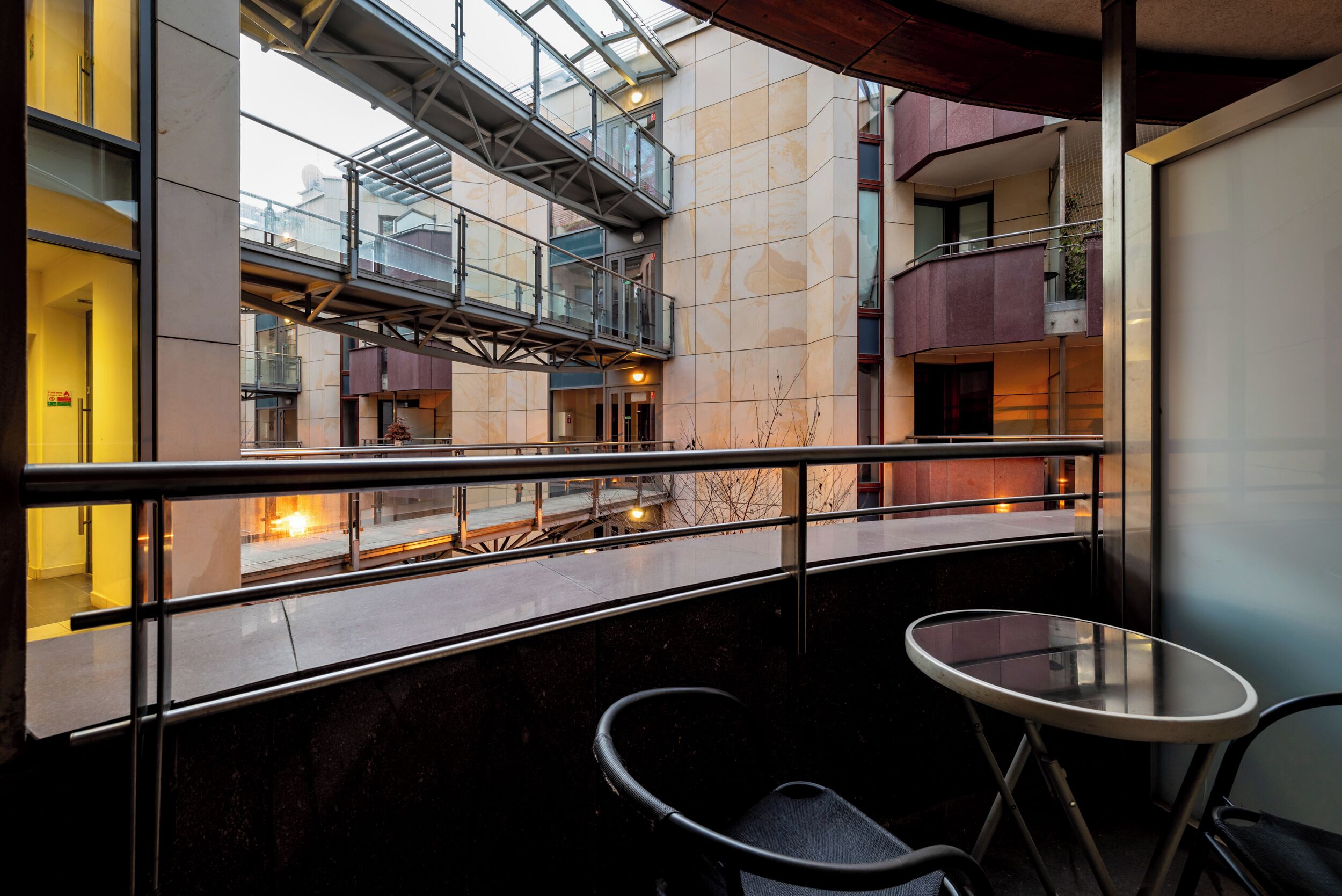 A modern interior with a glass balustrade, a small round table, and a chair.