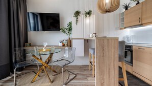 Eine moderne Küche mit Holzausbau, einem eingebauten Backofen und einem Essbereich mit Glastisch und Stühlen.
