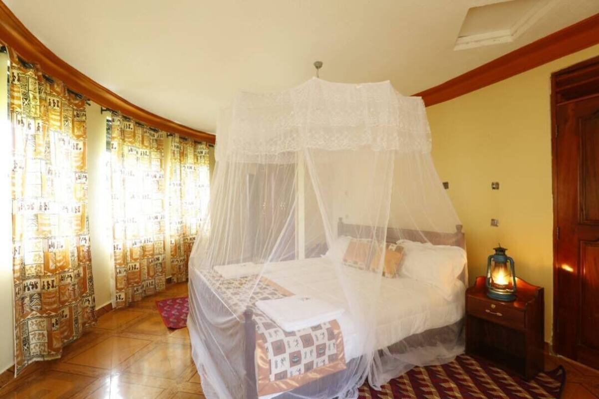 A bedroom with a canopy bed, a nightstand with a lantern, and patterned curtains.