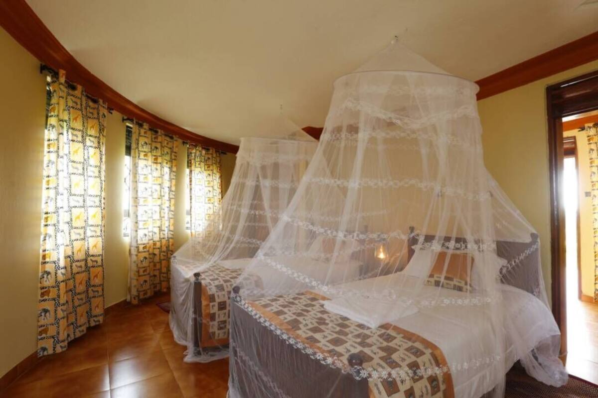 A room with a four-poster bed, a canopy, patterned curtains, and a tiled floor.