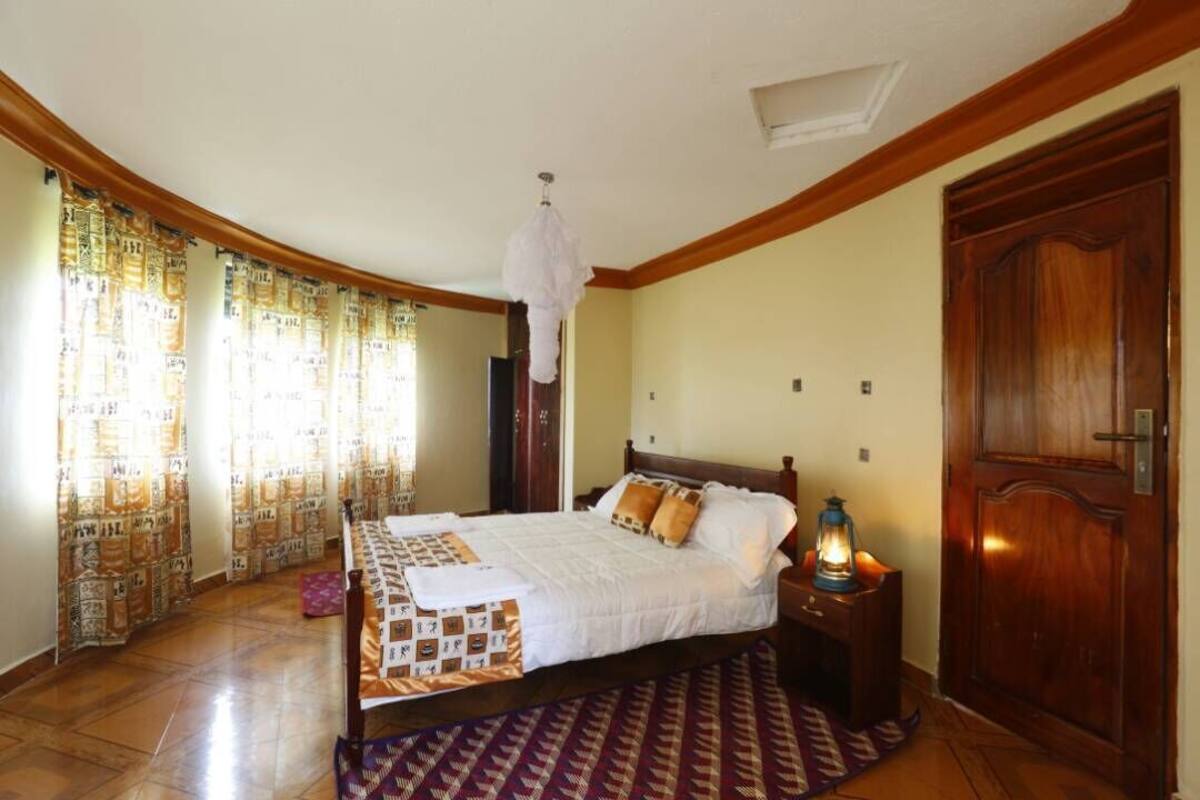 A bedroom with a bed, curtains, a wooden door, and a nightstand with a lantern.