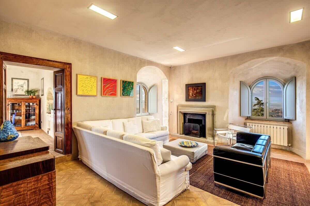 A living room with a sofa, ottoman, fireplace, and artwork on the wall.