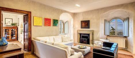 A living room with a sofa, ottoman, fireplace, and artwork on the wall.