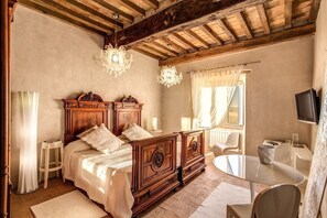 Ein Schlafzimmer mit einem hölzernen Himmelbett, einem kleinen runden Tisch und einem an der Wand montierten Fernseher.