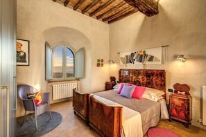 A bedroom with a large bed, a chair, a radiator, a window, and artwork on the wall. - Torre Fortunata, Splendidly Restored Medieval Tower Near Todi in Umbria (Todi)