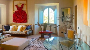 Ein gemütliches Wohnzimmer mit einer Couch, einem roten Sessel, einem Glastisch und einem Fenster mit Aussicht.