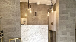 A reception area with a marble reception desk, a gold-framed chair, and a modern light fixture. - The Barn Tokyo (Tokyo)