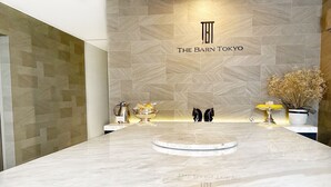 A modern hotel reception area with a marble counter, a logo above the counter, and a wall with a geometric pattern. - The Barn Tokyo (Tokyo)