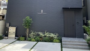 A modern building with a dark facade, two visible windows, and a door with a sign reading "THE BARN TOKYO". - The Barn Tokyo (Tokyo)