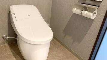 Un inodoro moderno con un panel de control y un dispensador de papel higiénico en la pared.