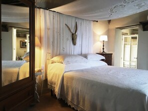 A bedroom with a large bed, a mirror, a nightstand, and a lamp. - Il Podere di Metato, Restored Tuscan Farmhouse with Pool with Views of Hills and Sea (Metato)