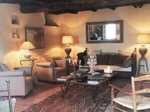 A cozy living room with a sofa, armchairs, a coffee table with books and candles, and a fireplace. - Il Podere di Metato, Restored Tuscan Farmhouse with Pool with Views of Hills and Sea (Metato)