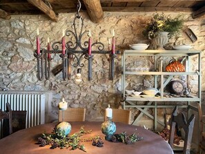 A rustic dining area with a stone wall, a chandelier, and a shelf with decorative items. - Il Podere di Metato, Restored Tuscan Farmhouse with Pool with Views of Hills and Sea (Metato)