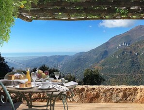 A table set outdoors with a scenic mountain view, a glass of juice, and a basket of fruit. - Il Podere di Metato, Restored Tuscan Farmhouse with Pool with Views of Hills and Sea (Metato)