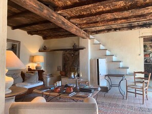 A rustic interior with a stone fireplace, a wooden table with books, and a cozy seating area.