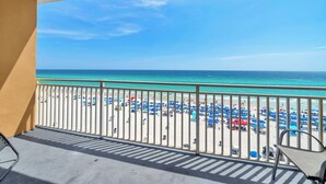 A balcony with a view of a beach with umbrellas and people. - ⭐Beachfront-Beach Service-Fab Pool-Splash 303E⭐ (Panama City Beach)