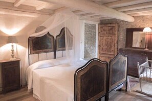 Ein Schlafzimmer mit einem Himmelbett, einem Holzschrank und einem Nachttisch mit Lampe.