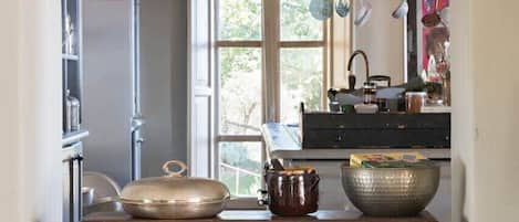 Una cocina con una mesa de madera, ollas colgantes y una ventana con vistas.