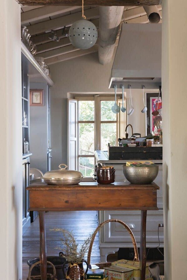 Una cocina con una mesa de madera, ollas colgantes y una ventana con vistas.