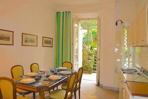 A dining area with a table set for four, chairs, and framed pictures on the wall.