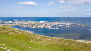 Vista aérea de un puerto deportivo con barcos amarrados, un muelle y edificios al fondo.