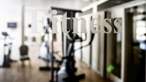 Interior borroso de un gimnasio con equipo de ejercicio y un gran letrero que dice 'Fitness'.