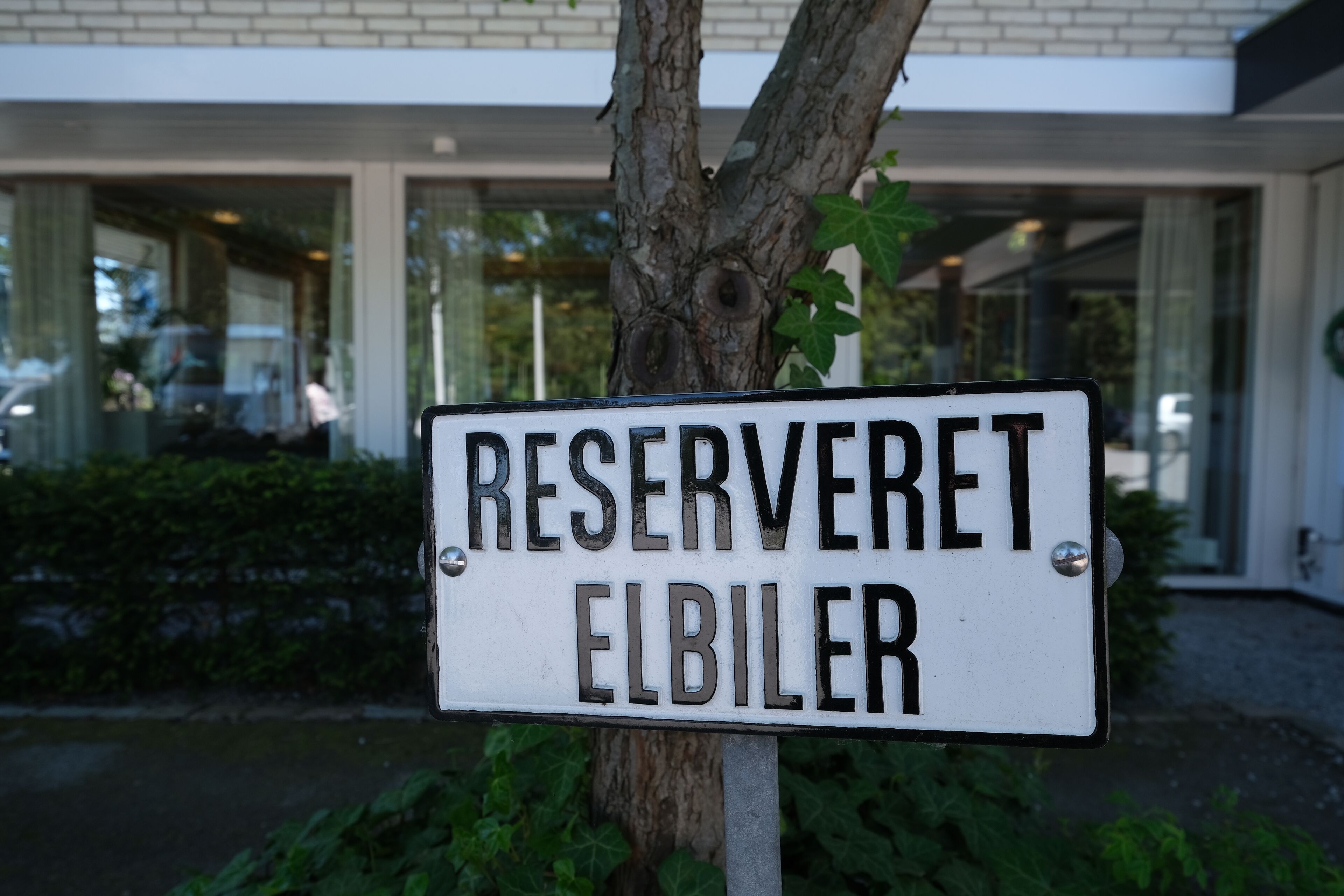 Une plaque portant l’inscription « RESERVERET ELBILER » est fixée sur un poteau métallique.