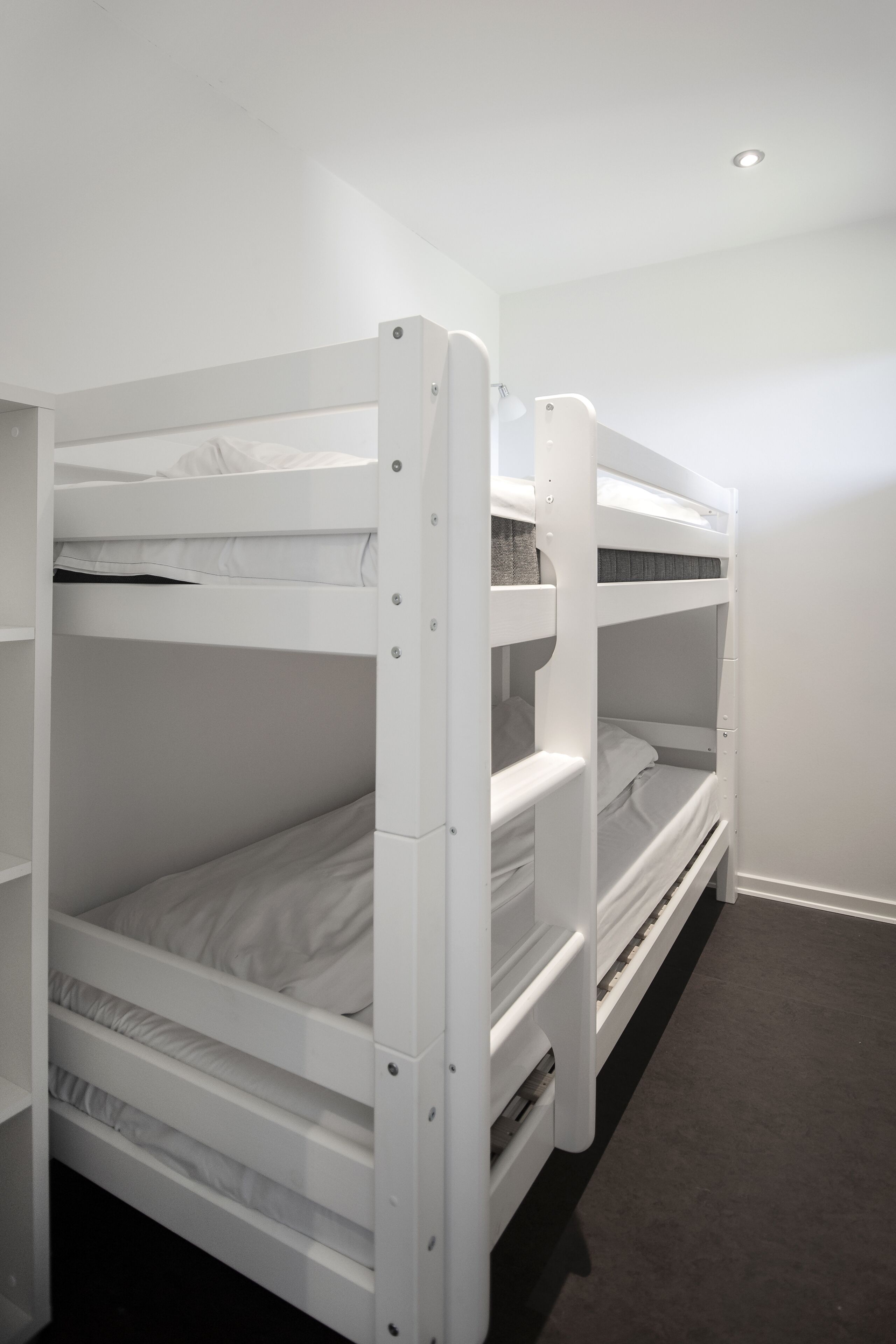 A bunk bed room with white bedding and a carpeted floor.