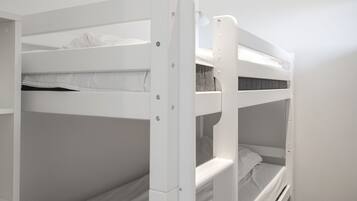 Une chambre avec un lit superposé, dotée de linge de lit blanc et d’un sol recouvert de moquette.