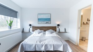 Un dormitorio con una cama grande, una ventana con vistas a la playa y un cuadro sobre la cama.