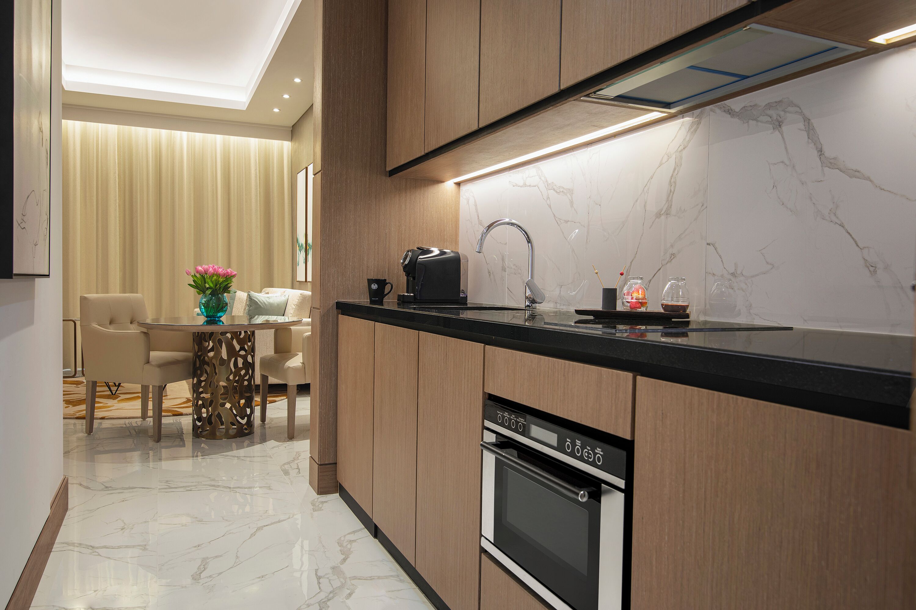 A modern kitchen with a black countertop, stainless steel appliances, and a dining area with a table and chairs.