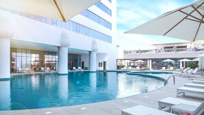 A large indoor swimming pool with multiple levels of balconies and sun loungers. - Al Jaddaf Rotana Suite Hotel (Dubai)