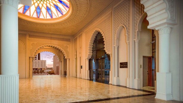 A spacious lobby with a high ceiling, ornate arches, and a large stained glass window. - Al Jaddaf Rotana Suite Hotel (Dubai)