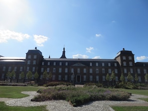 A large, historic building with symmetrical architecture, featuring multiple windows and a central tower.