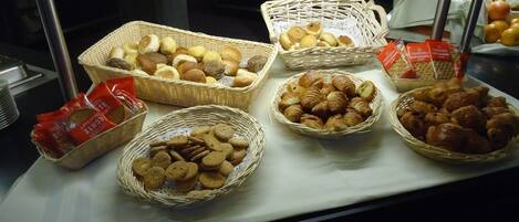 A display case with various baked goods including bread, croissants, and cookies.