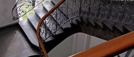 Una escalera con barandales de metal ornamentados y pasamanos de madera.
