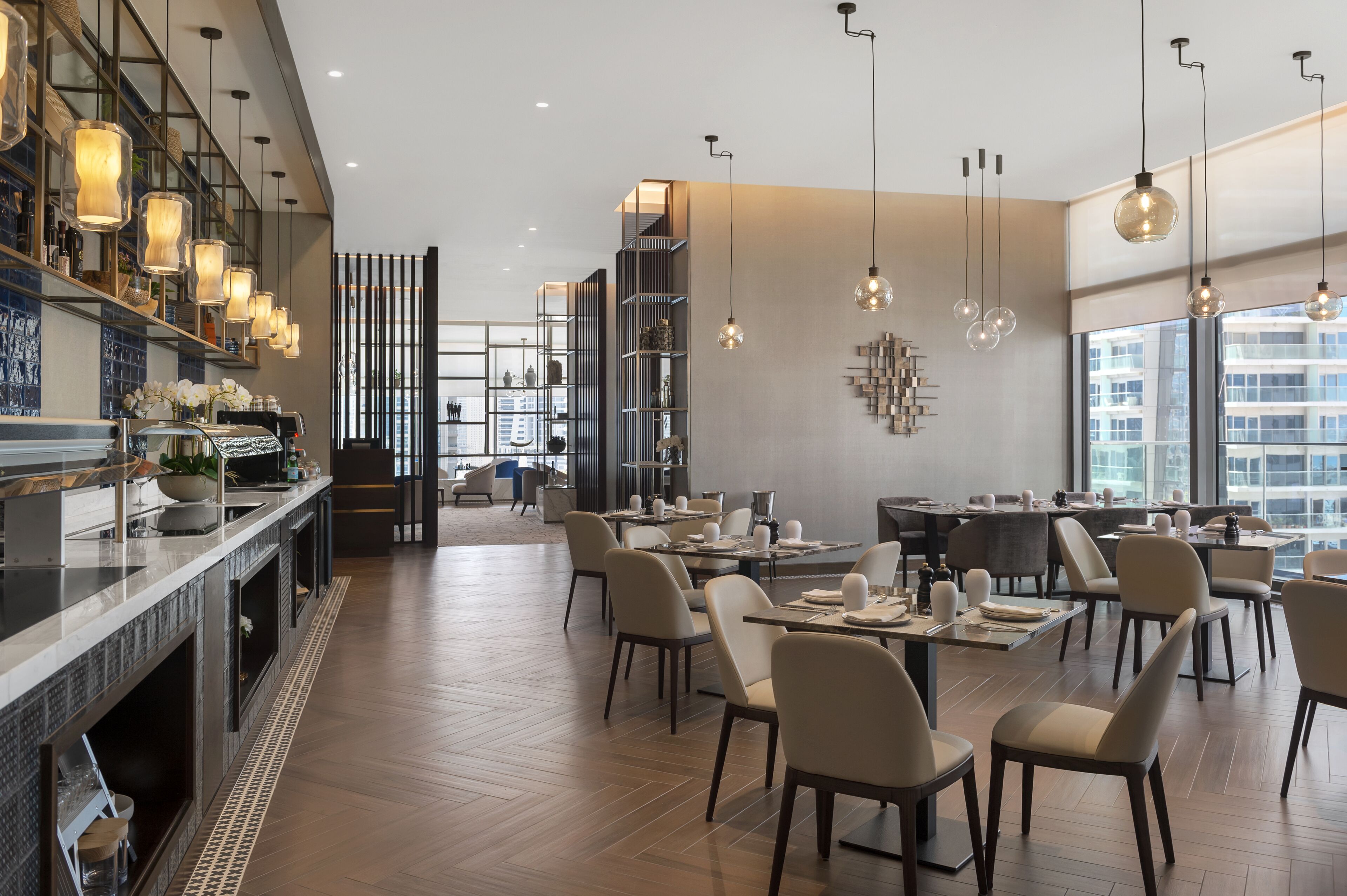Un ristorante moderno con un lungo bancone, diversi tavoli e lampade a sospensione.