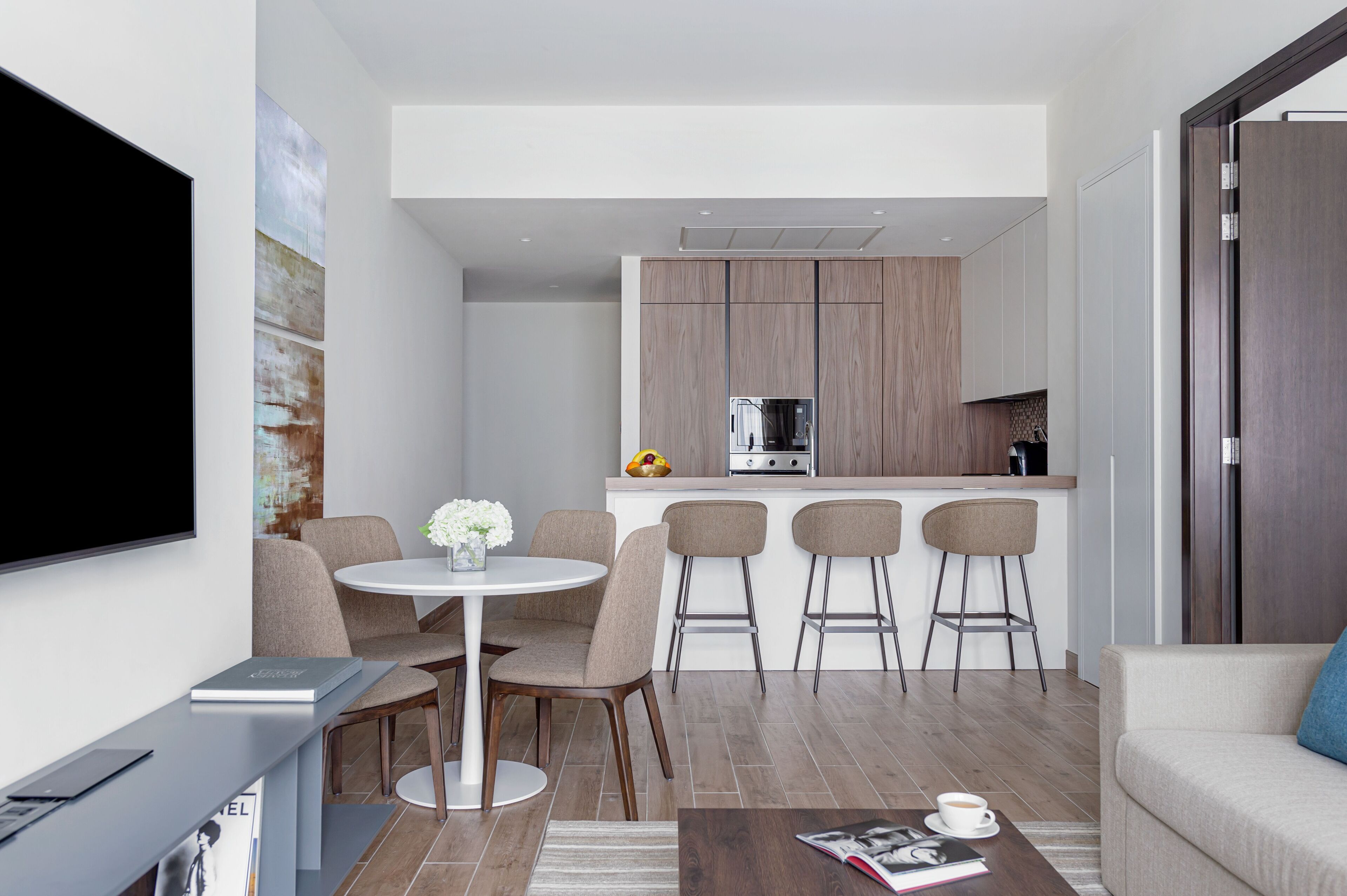 A modern living room with a dining area, a kitchen, and a TV.