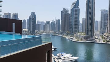 A high-rise building with a rooftop pool overlooking a marina with boats.