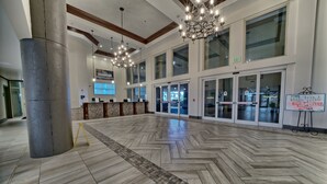 A spacious lobby with a herringbone patterned floor, large windows, and a reception desk. - Shores of Panama 527~2 Bedroom/2bath (Panama City Beach)