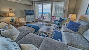 A living room with a sofa, chairs, a coffee table, and a TV. - Shores of Panama 527~2 Bedroom/2bath (Panama City Beach)