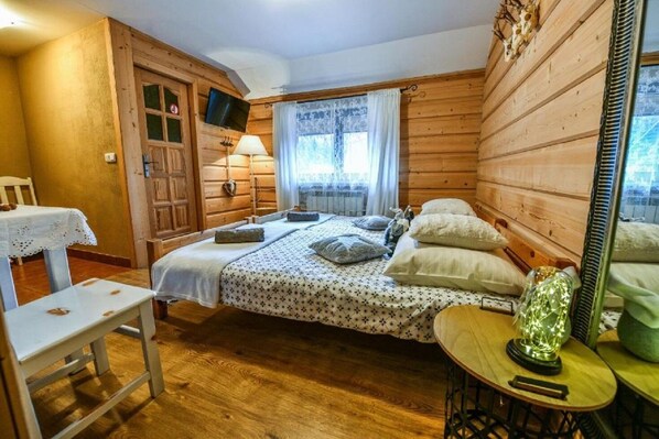 A cozy wooden cabin room with a bed, a small table, and a chair. - Willa Bachledowka (Zakopane)