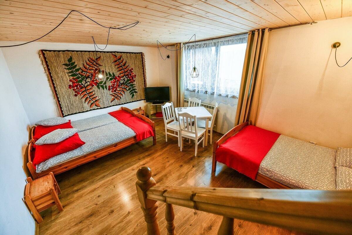 A room with two wooden beds, a desk, and a chair.