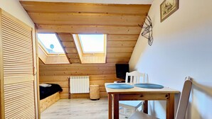 A cozy attic room with wooden beams, a skylight, a radiator, and a table with two chairs. - Willa Bachledowka (Zakopane)
