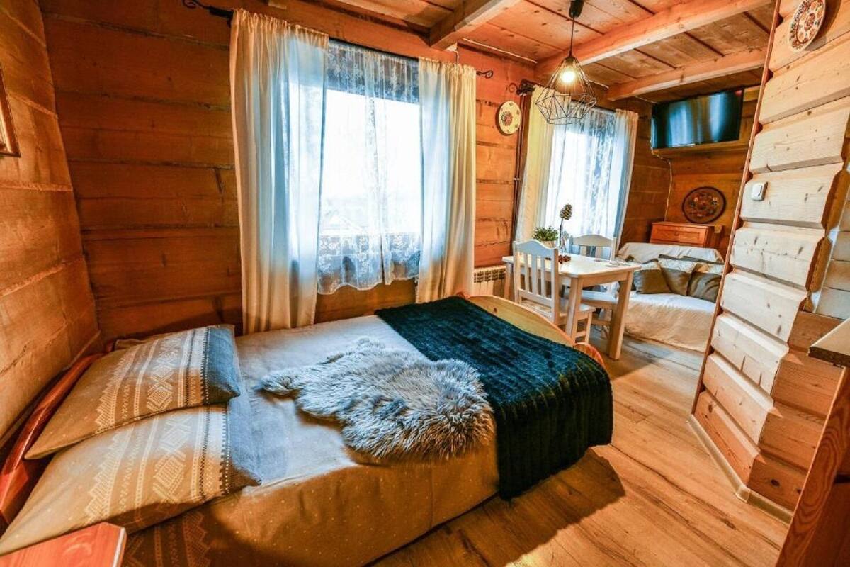 A cozy log cabin bedroom with a bed, a small table, and a chair.