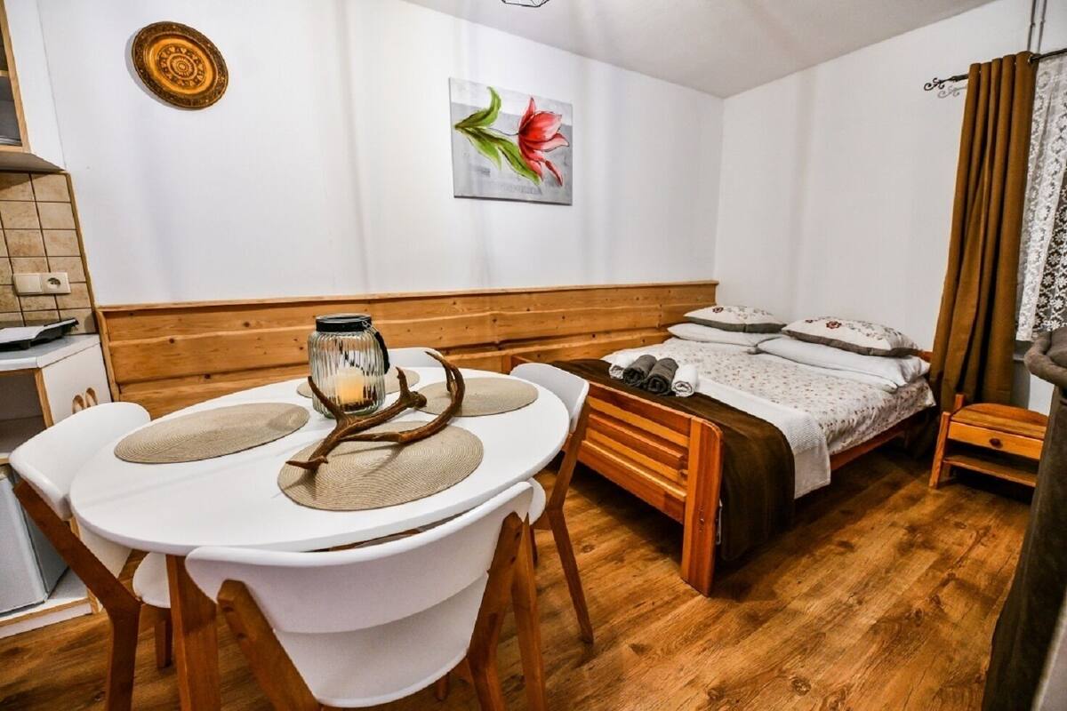 A cozy room with a wooden bed, a dining table with a candle, and a painting on the wall.