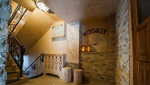 A cozy stairwell with a wooden handrail, a stone wall with a fireplace, and a sign reading "WITOJCIY". - Willa Bachledowka (Zakopane)